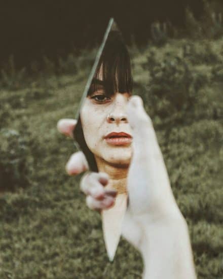 woman holding broken mirror